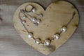 A wooden heart for Valentine`s Day with silver ornaments, earrings, rings, necklaces with pearls, diamonds, precious stones, rhin