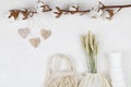 Wooden hearts handing on cotton flower and eco natural paper cups, string bag, wheat on white background Royalty Free Stock Photo