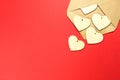 Wooden hearts spill out of an open envelope on a red background. Valentine`s Day, love letter, declaration of love, acquaintance. Royalty Free Stock Photo