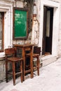 Wooden high table and two chairs near the wall of a small bar on the street