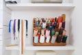 Wooden holder with collection of different threads on shelf in tailor studio