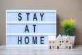 Wooden Home model and lightbox with text STAY AT HOME on table. Coronavirus, Covid-19, Quarantines and Social Distancing concept