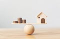 Wooden home and money coins stack on wood scale. Property investment and house mortgage financial real estate concept Royalty Free Stock Photo