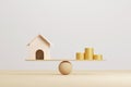 Wooden home and money coins stack on wood scale Royalty Free Stock Photo