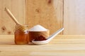 Wooden honey dipper in honey bottle and sugar in bowl and cocoa