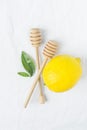 Wooden Honey Dippers Ripe Yellow Lemon Green Citrus Leaves on White Cotton Linen Fabric Background. Organic Cosmetics