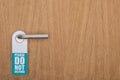 Wooden hotel room door with please do no disturb sign on handle