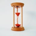 Wooden hourglass on white background with red sand