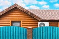 Wooden house with air conditioning, surrounded by a blue fence. Blue sky with clouds Royalty Free Stock Photo