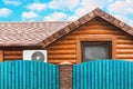 Wooden house with air conditioning, surrounded by a blue fence. Blue sky with clouds. Bright colors Royalty Free Stock Photo