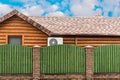 Wooden house with air conditioning, surrounded by a green fence. Blue sky with clouds. General plan Royalty Free Stock Photo