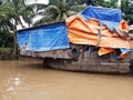 Wooden house boat anchored in the Mekong river. Old boat covered with canvas of different colors. Vietnamese culture and Royalty Free Stock Photo