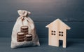 Wooden house and cash coins money bag. Buying and selling real estate. Taxes. Mortgage loan. Sale of housing. Proposal for a deal