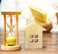 Wooden house and clock. Businessman counting money. Payment of deposit or advance payment for renting a home or apartment. Long- Royalty Free Stock Photo