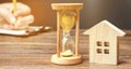 Wooden house and clock. A person signs documents. Signing a contract to rent a house or apartment. Making a will. Testament Royalty Free Stock Photo