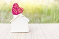 Wooden house with design red wooden heart over blurred green garden background Royalty Free Stock Photo