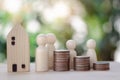 A wooden house and wooden dolls with stack of coins concept for planning the future, hope