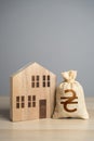 Wooden house figure and ukrainian hryvnia money bag. Taxes. Property value appraisal. Make a deal. Buying and selling real estate Royalty Free Stock Photo