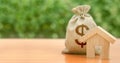 Wooden house figurine and money bag with a dollar symbol. Budget, subsidized funds. Mortgage loan for purchase housing Royalty Free Stock Photo