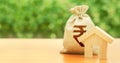 Wooden house figurine and money bag with indian rupee INR symbol. Budget, subsidized funds. Mortgage loan for purchase housing,