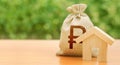 Wooden house figurine and a money bag with a russian ruble symbol. Mortgage loan for the purchase of housing. Down payment first