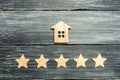 Wooden house and five stars on a gray background. Rating of houses and private property. Buying and selling, renting apartments. T Royalty Free Stock Photo