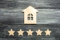 Wooden house and five stars on a gray background. Rating of houses and private property. Buying and selling, renting apartments. T Royalty Free Stock Photo