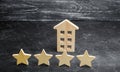 Wooden house and four stars on a gray background. Rating of houses and private property. Buying and selling, renting apartments. Royalty Free Stock Photo