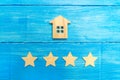 Wooden house and four stars on a gray background. Rating of houses and private property. Buying and selling, renting apartments. T Royalty Free Stock Photo