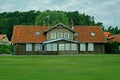 Old village wooden house front yard with red roof and forest behind Royalty Free Stock Photo