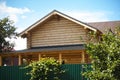 A wooden house with a grey roof behind a green fence with plants growing on it Royalty Free Stock Photo