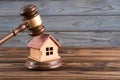 Wooden house, judge`s gavel on wooden background. Royalty Free Stock Photo