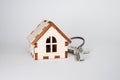 Wooden house with key on gray background, concept for selling houses with copyspace Royalty Free Stock Photo