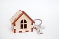 Wooden house with key on white background, concept for selling houses with copyspace Royalty Free Stock Photo