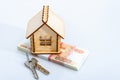 A wooden house with keys on a bundle of Russian banknotes. White background Royalty Free Stock Photo