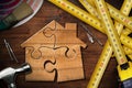 Wooden House made of Puzzle Pieces on Workbench with Work Tools Royalty Free Stock Photo