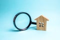 Wooden house and magnifying glass on a blue background. Buying and selling real estate, building new buildings, offices and homes Royalty Free Stock Photo