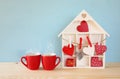Wooden house with many hearts next to coffee cups