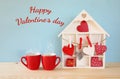 Wooden house with many hearts next to coffee cups