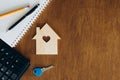 Wooden house model, calculator and key on a wooden table, flat lay. Royalty Free Stock Photo