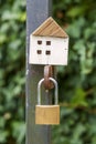 Wooden house model a on a closed gate with a padlock Royalty Free Stock Photo