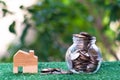 Wooden house model and glass jar with coins inside. Home mortgage and property investment concept. Copy space