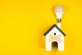 Wooden house model and lcd lamp on  yellow background. Concept, new idea, home repair Royalty Free Stock Photo