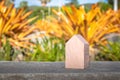 Wooden house model toy on top of concrete wall with green natural in background. Royalty Free Stock Photo