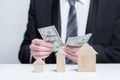 Wooden house models and us money dollars in businessman hands, buying property, security, insurance concept