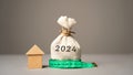 Wooden house and money bag 2024. Family budget planning for next year. Investments, plans, savings. Mortgage rates. Real estate
