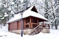 Wooden house in mountain in winter time. Log cabin in forest alone in wilderness. Wooden house with a wooden roof against Royalty Free Stock Photo
