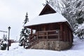 Wooden house in mountain in winter time. Log cabin in forest alone in wilderness. Wooden house with a wooden roof against Royalty Free Stock Photo