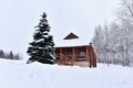 Wooden house in mountain in winter time. Log cabin in forest alone in wilderness. Wooden house with a wooden roof against Royalty Free Stock Photo