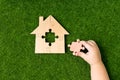 Wooden house of puzzles, the missing element in the hands Royalty Free Stock Photo